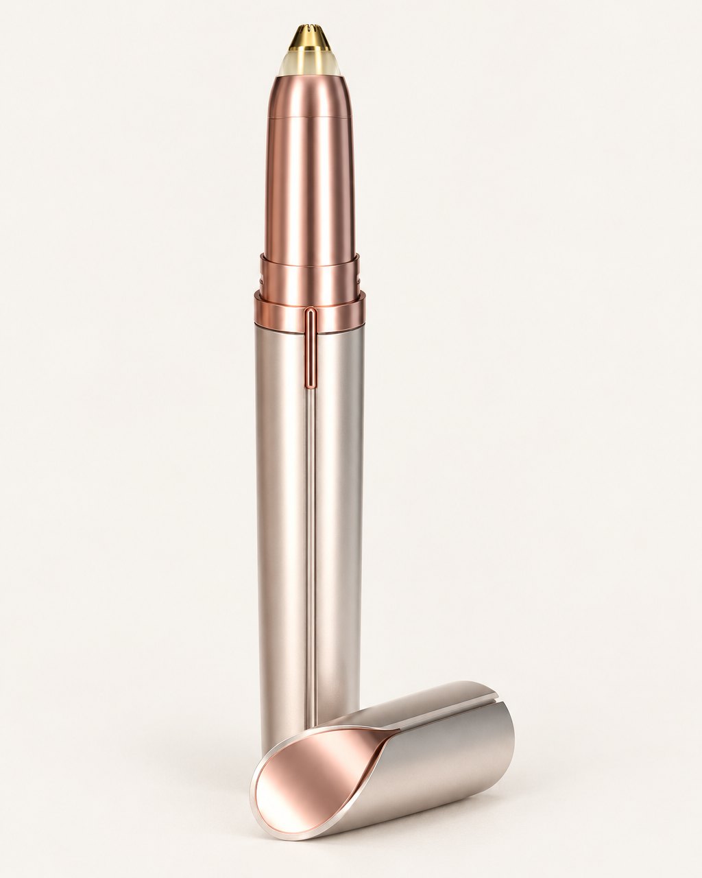 Rose-gold electric brow trimmer with its cap beside it, on a light background