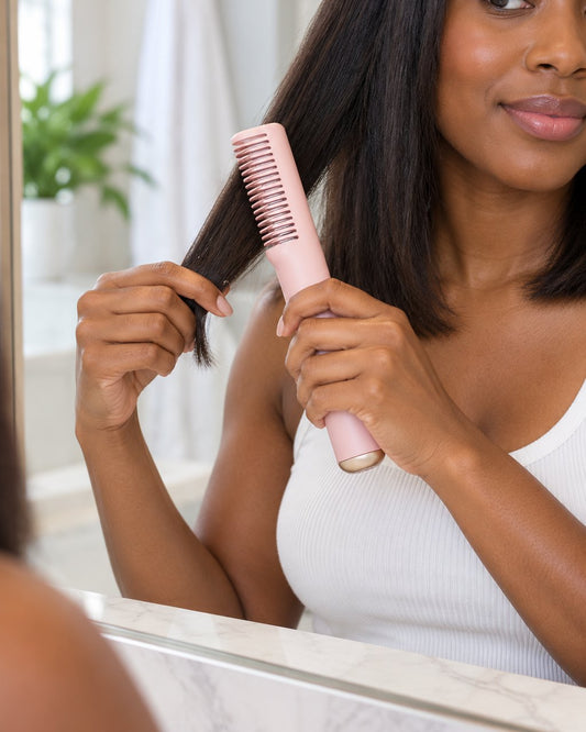 A woman combs the heated comb through the ends of a section of her shoulder-length hair