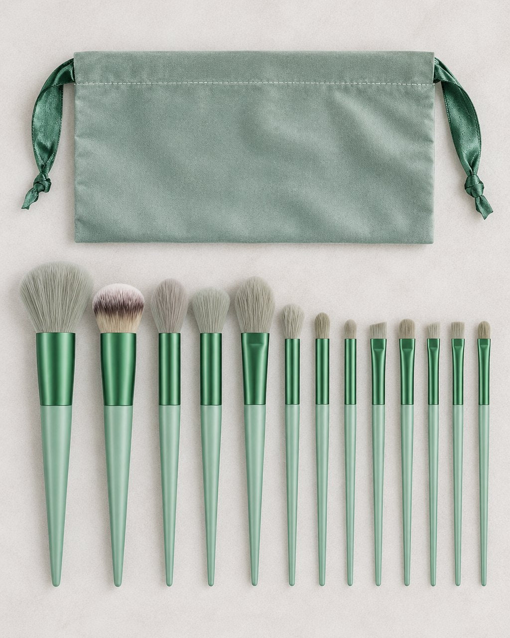 All thirteen sage green brushes laid out in a row beside the pouch