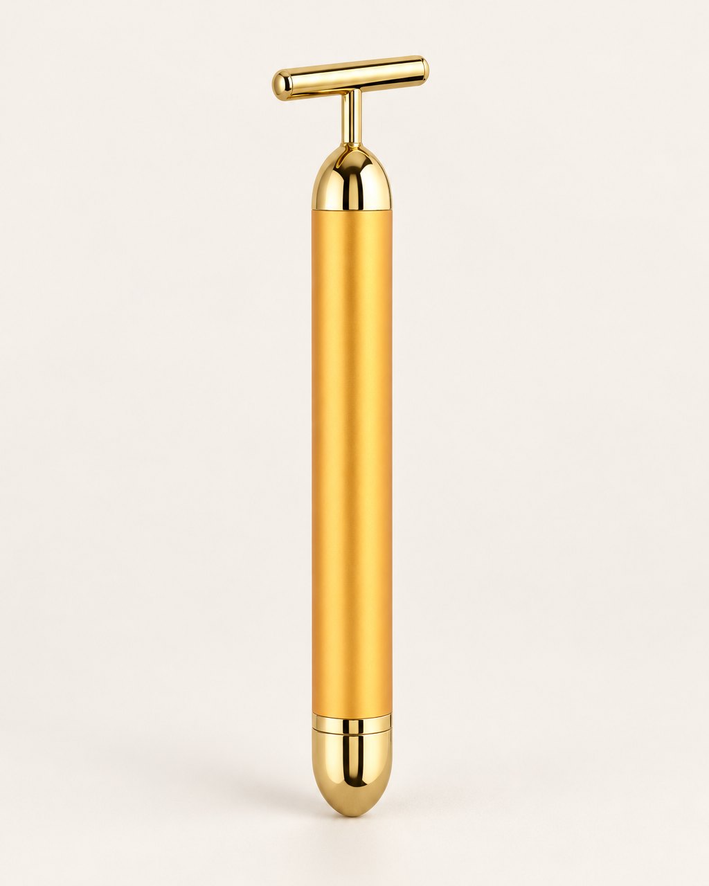 Gold-tone vibrating beauty bar with a T-shaped head, standing upright on a light background