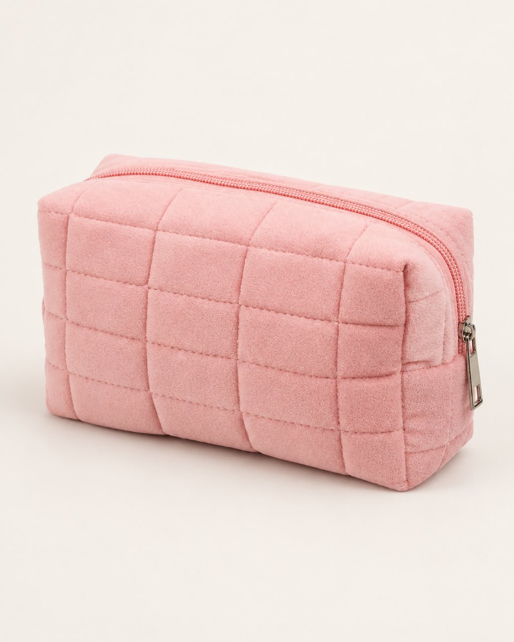 Pink puffy quilted makeup bag with a zip on a light background