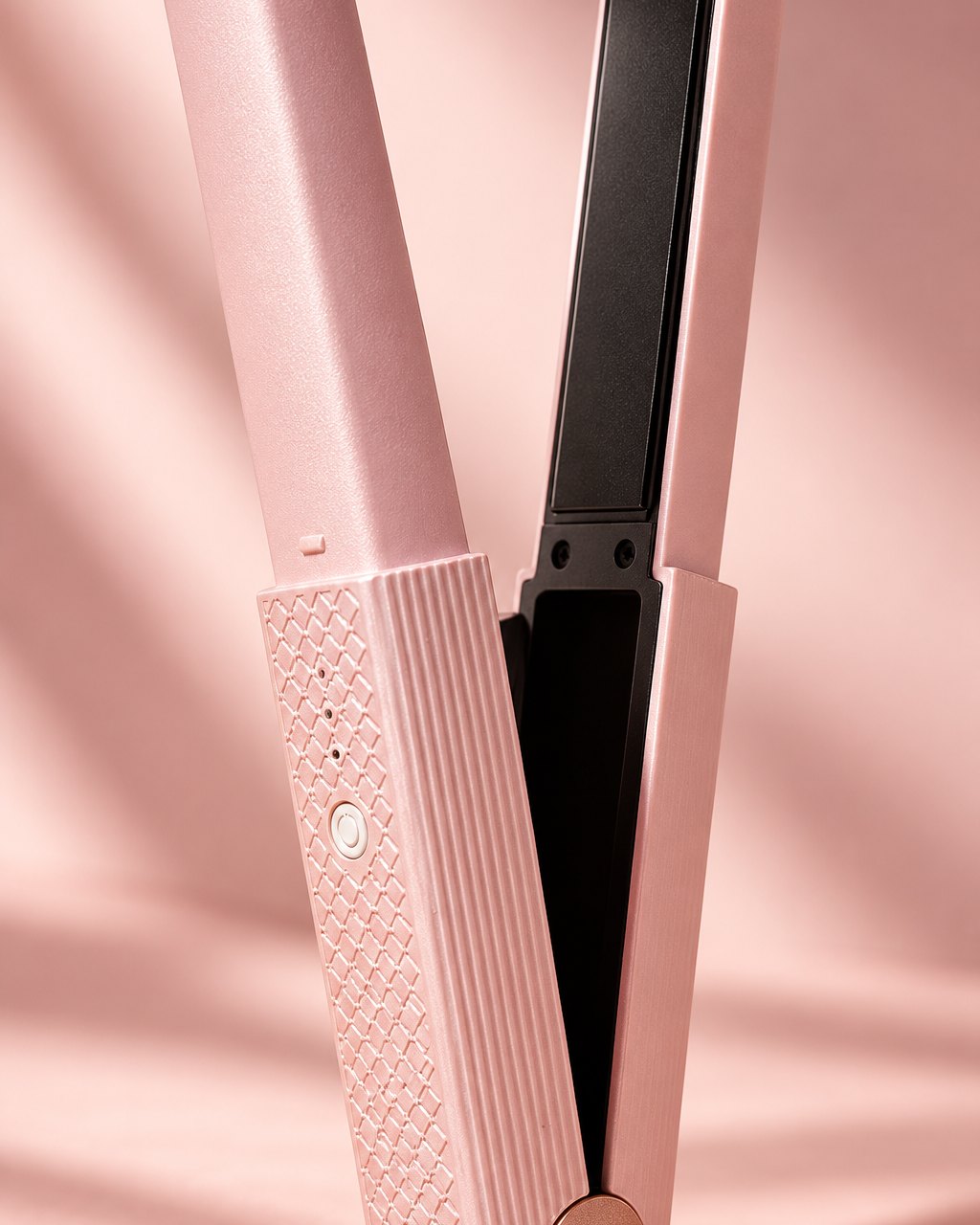 Close-up of the open mini flat iron's black ceramic plate, diamond-textured grip and single round button