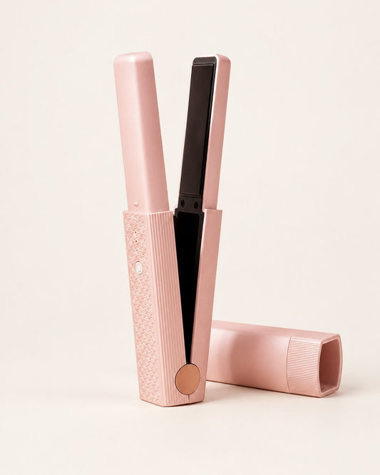 Pink cordless mini flat iron standing open beside its cap on a light background
