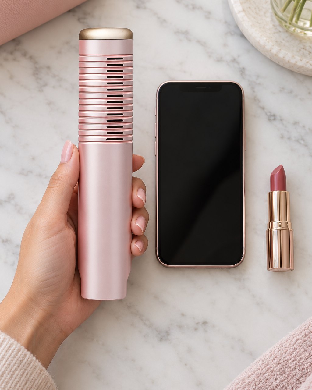 The comb held upright in one hand beside a lipstick and a phone