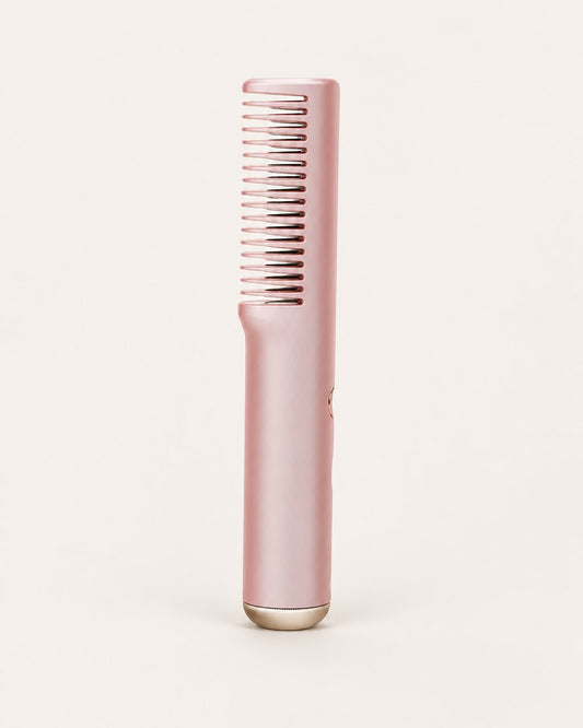 Pink cordless straightening comb with its single row of heated teeth, on a light background