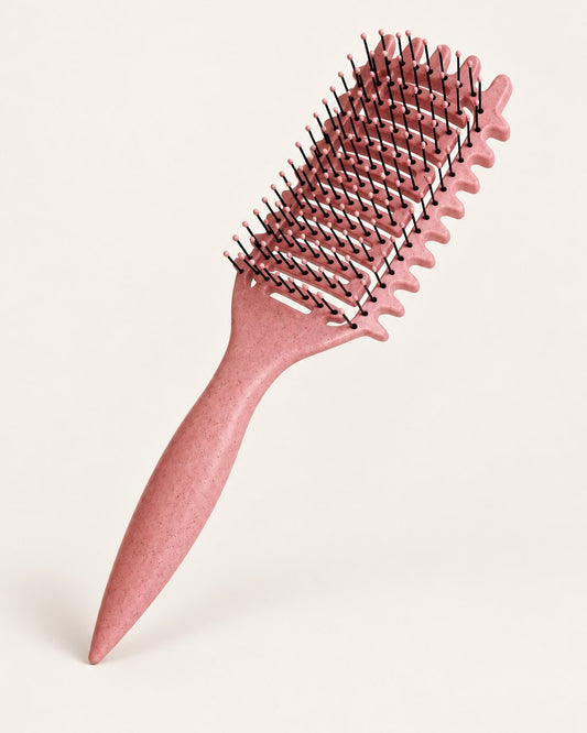 Pink speckled curl defining brush with black bristles on a light background