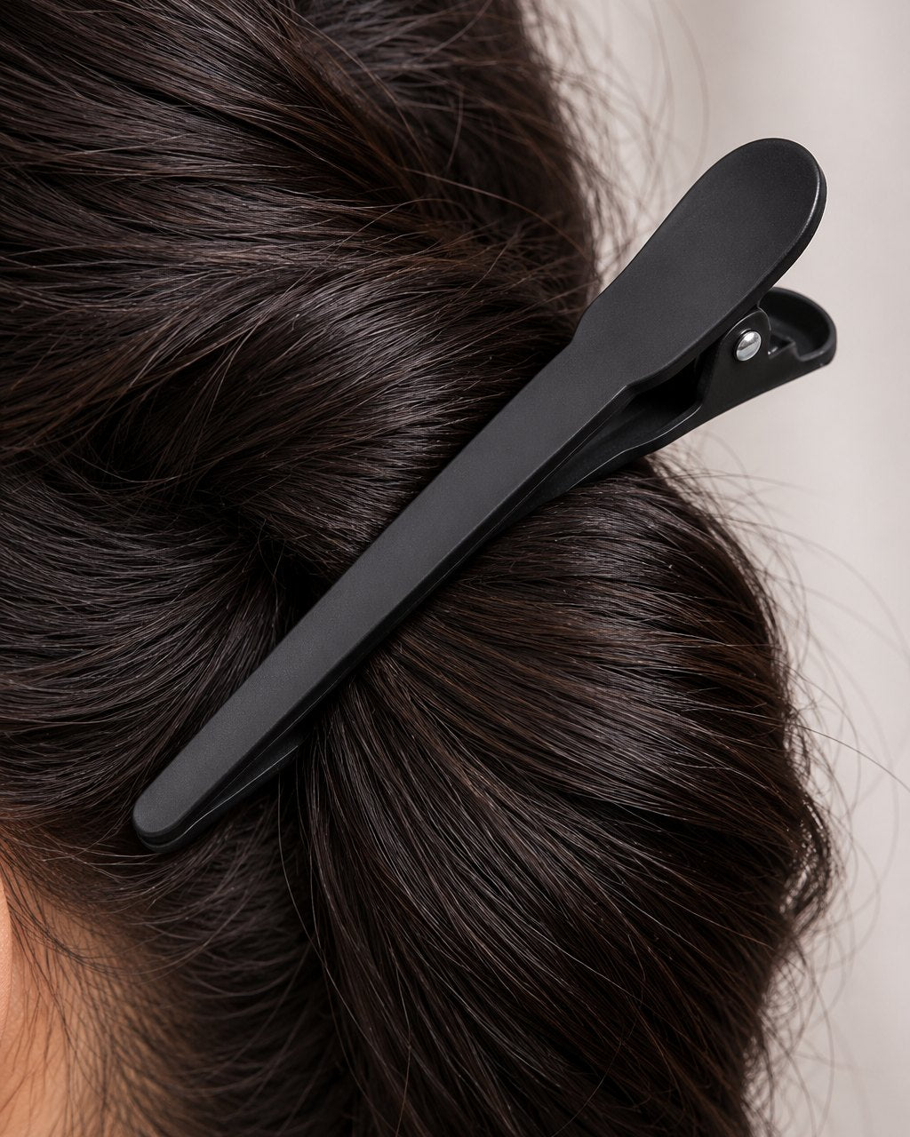 Close-up of a clip's long matte jaws gripping a thick section of hair