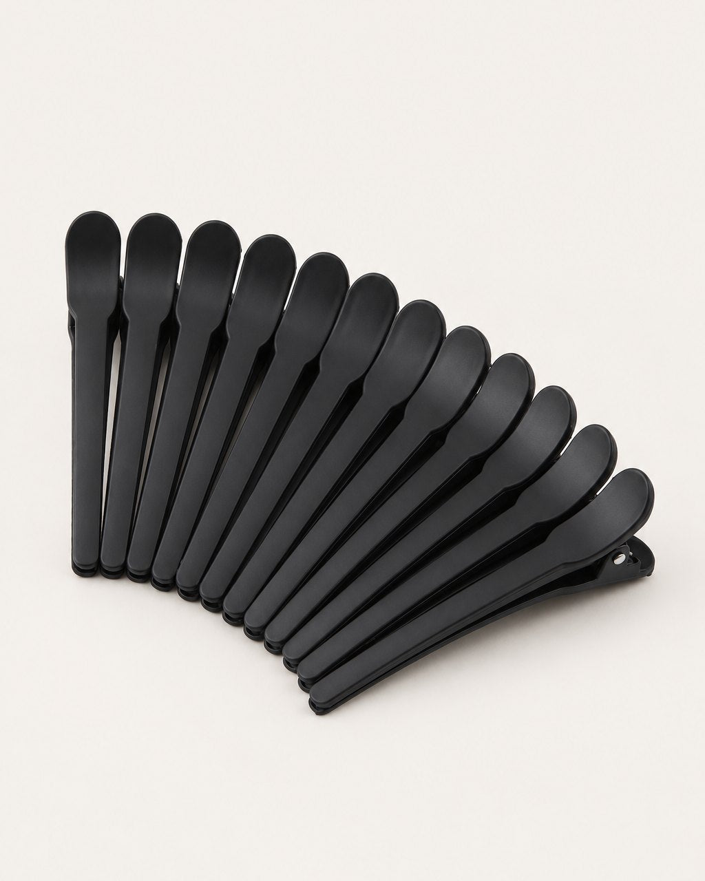 Twelve matte black duckbill sectioning clips fanned out on a light background