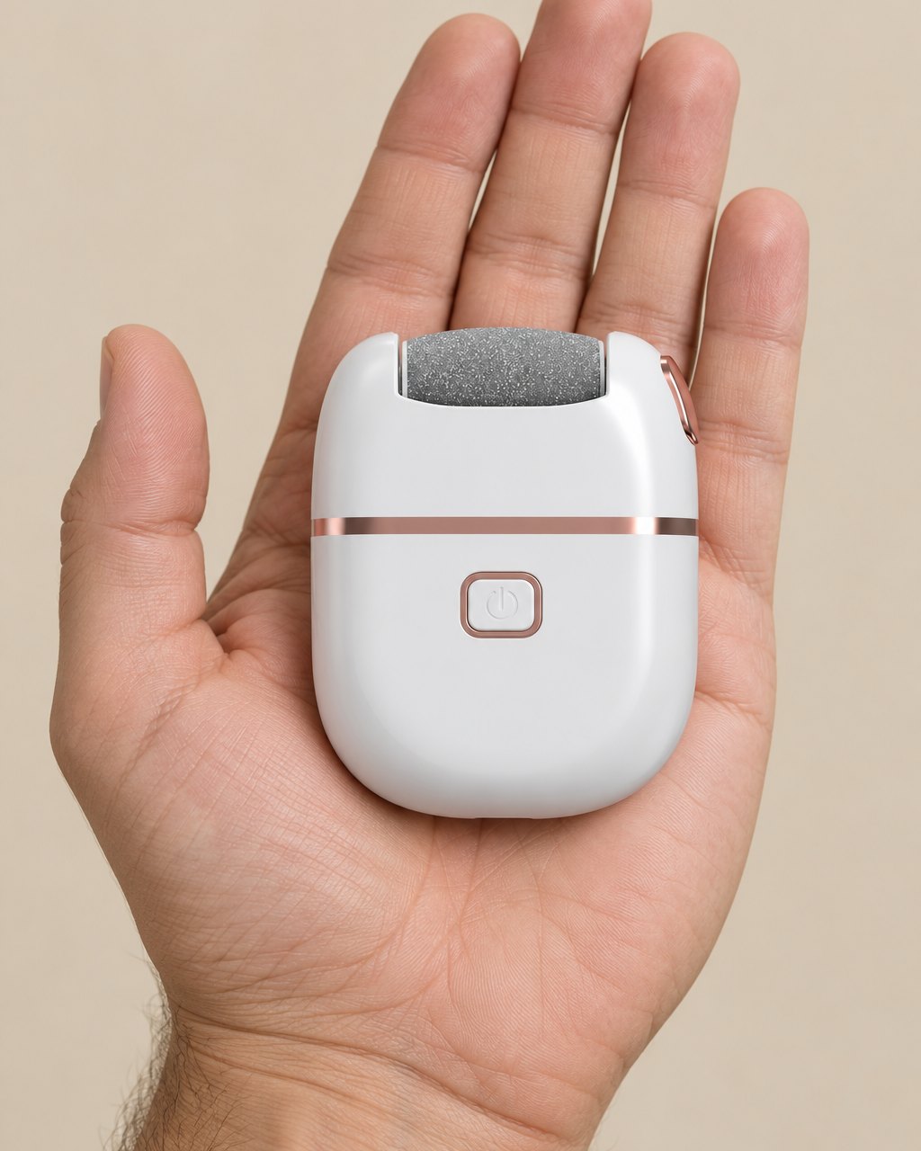 The callus remover held in one hand, showing its palm-sized body