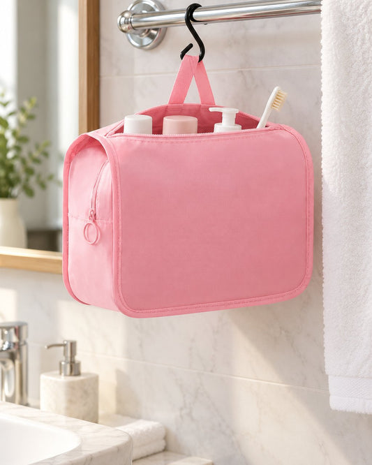 Pink toiletry bag hanging by its hook from a hotel towel rail, toiletries peeking out of the open zip
