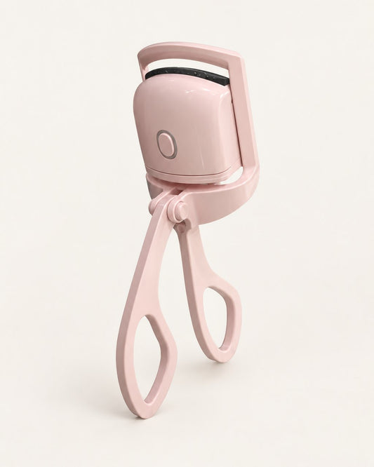Pink heated lash curler with scissor handles, standing on a light background