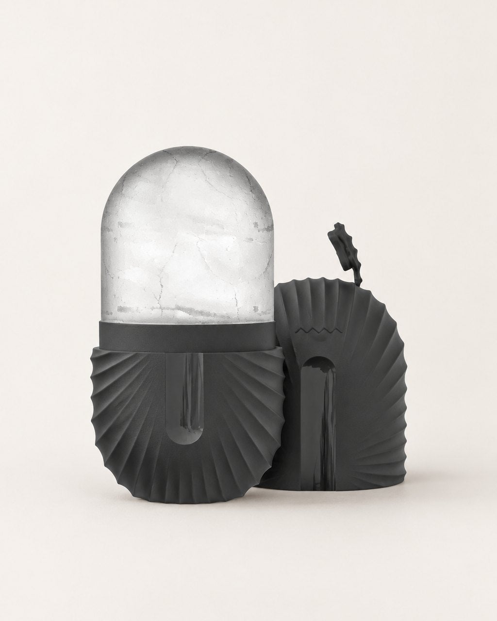 Black ribbed silicone ice capsule holding a clear dome of ice, cap beside it