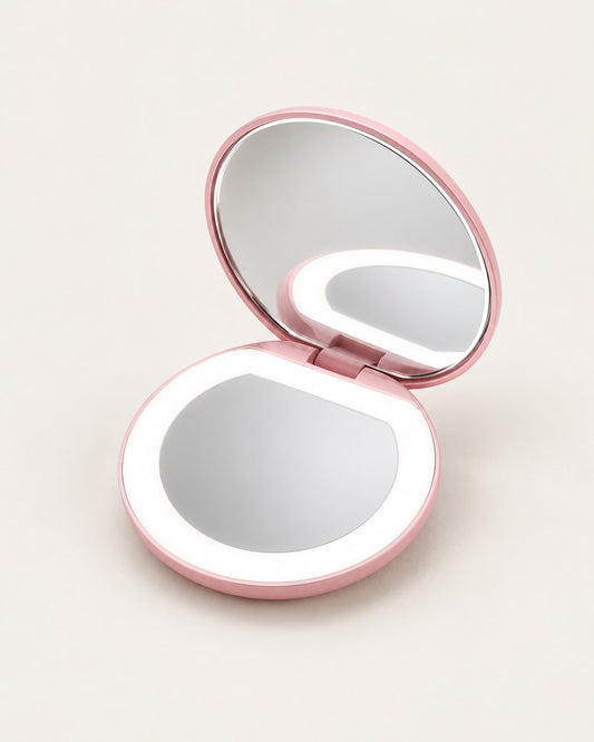Pink round LED compact mirror, open, with its light ring on a light background