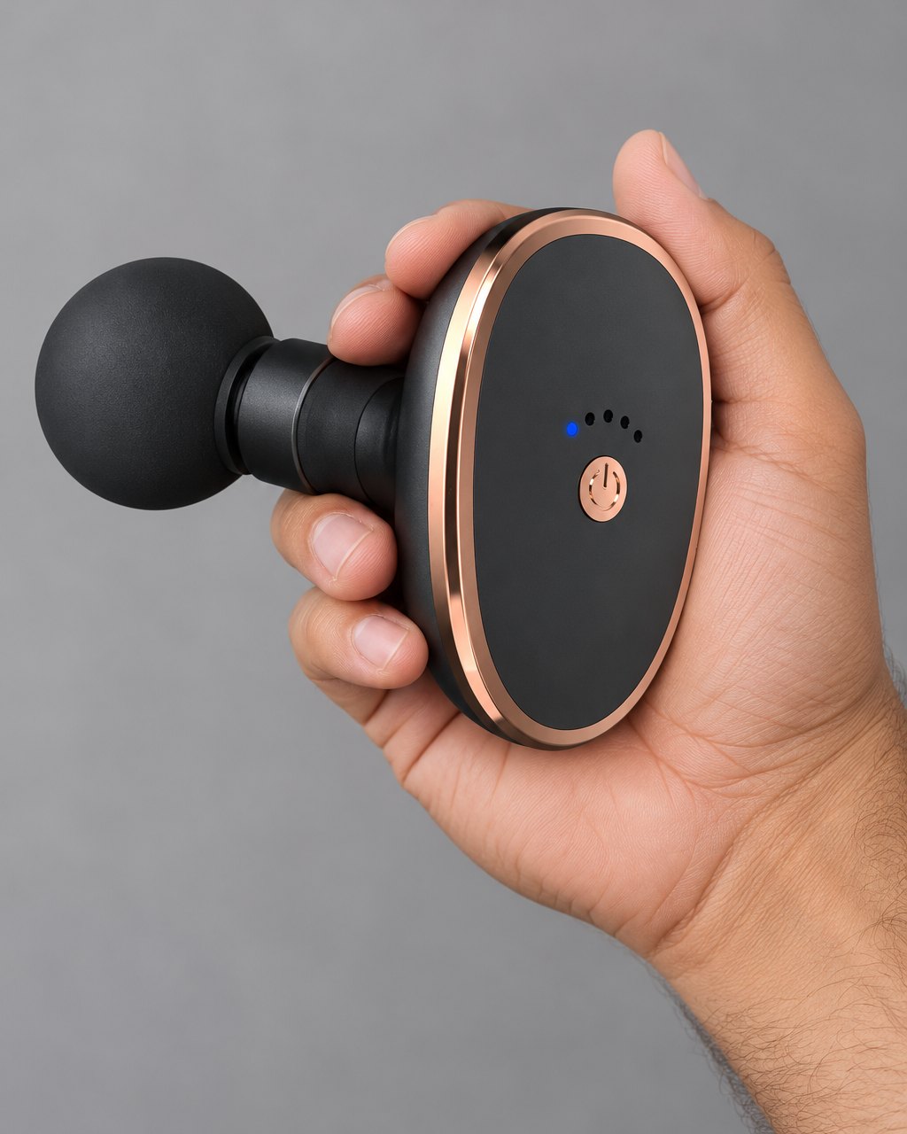 The mini massage gun resting in one hand, its oval body no bigger than the palm