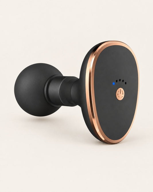 Black mini massage gun with a round head and rose-gold-tone trim on a light background