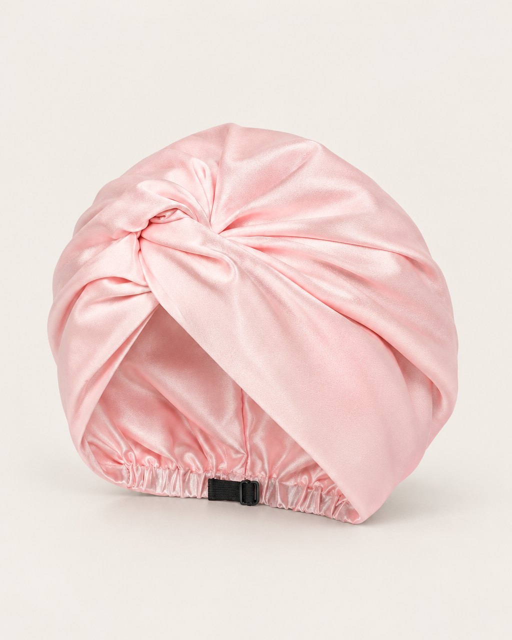 Pink satin twist turban with a twisted front on a light background