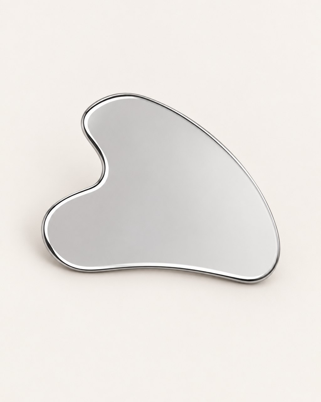 Heart-shaped stainless steel gua sha with a mirror finish on a light background
